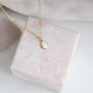 A tiny synthetic glowing opal teardrop pendant secured to a gold filled chain necklace at the length of your choice.