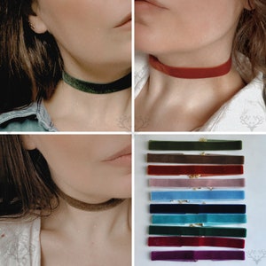 May include: A collection of velvet chokers in various colors, including green, brown, red, and blue. The chokers are displayed on a white surface and worn around the neck. Each choker has a gold-colored clasp.