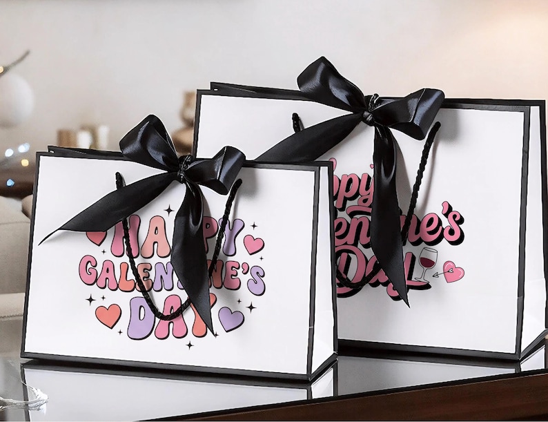 Pu&ograve; includere: Due sacchetti regalo bianchi con bordi e manici neri, ciascuno ornato da un grande fiocco di raso nero. Le borse presentano il testo "Happy Galentine's Day" in un font retr&ograve; colorato, insieme a grafiche a forma di cuore.