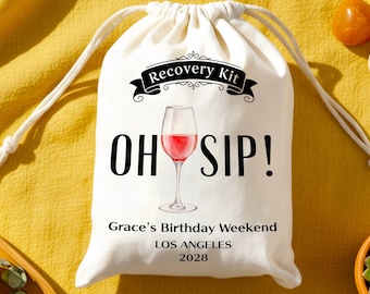 May include: A white drawstring bag featuring the text "Recovery Kit" above "OH SIP!" and a watercolour image of a wine glass filled with red wine. The bag also includes "Grace's Birthday Weekend LOS ANGELES 2028".