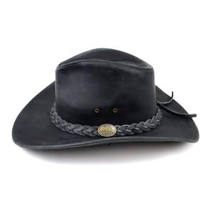 May include: Black leather cowboy hat with a braided band around the crown. The hat has a wide brim and a small metal emblem on the band. The hat is a dark gray color and appears to be made of leather.