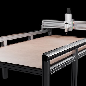 Peut inclure: Une machine CNC avec une surface de travail marron clair et un cadre en métal argenté. La machine est équipée d'un système de portique avec un outil de coupe, conçu pour la coupe et la fabrication de précision. Le fond est noir.