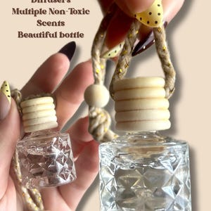 May include: Two clear, diamond-patterned glass car air fresheners with wooden tops and rope hangers. The text on the image reads "Non-Toxic Car Diffusers, Multiple Non-Toxic Scents, Beautiful bottle."