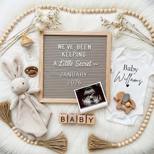 Könnte beinhalten: Baby-Ankündigung mit einer Buchstaben-Tafel mit der Aufschrift "We've been keeping a little secret ~ January 2026." Das Bild zeigt einen Baby-Body, Ultraschallbild, Holzblöcke mit "BABY" und ein Plüschkaninchen.