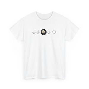 Può includere: T-shirt bianca con grafica nera. La grafica mostra una palla da biliardo con il numero 8 all'interno, incorporata in una linea di battito cardiaco, che termina con una forma di cuore. Un capo casual.