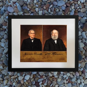 Puede incluir: Obra de arte enmarcada con dos retratos de hombres con trajes negros y pajaritas. Una placa dorada con nombres manuscritos está debajo. El marco es negro.