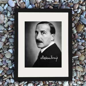 Könnte beinhalten: Schwarz-weiß gerahmtes Porträt eines Mannes mit Schnurrbart, der einen Anzug trägt. Das Bild enthält die handschriftliche Signatur "Stefan Zweig" in weißer Schrift. Das Porträt befindet sich vor einem weißen Hintergrund in einem schwarzen Rahmen.