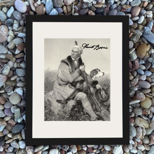 May include: Black framed print featuring a black and white illustration of Daniel Boone with his dog and rifle. The print has a white border and the name "Daniel Boone" is written in cursive.