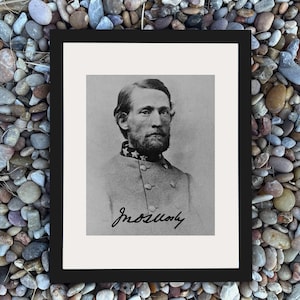 May include: Black and white framed portrait of a man with a beard and mustache. The man is wearing a military uniform with stars on the collar. The portrait has a signature at the bottom. The frame is black.