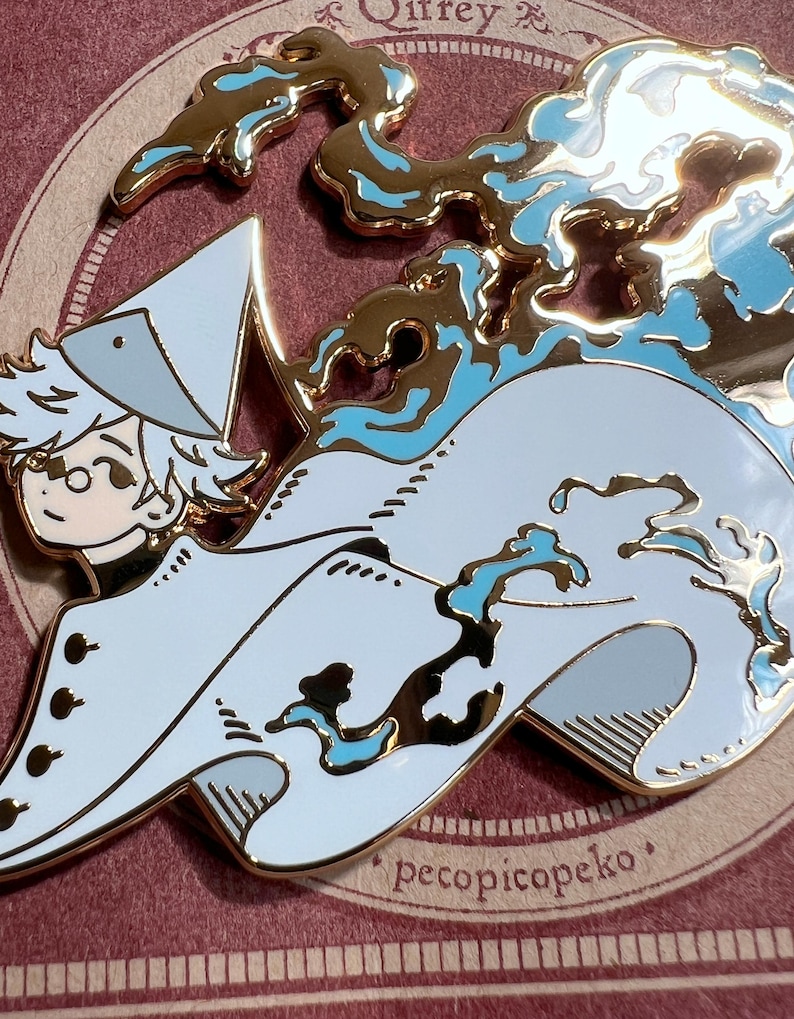 May include: A gold-colored enamel pin featuring a cartoon character with white hair and a hat, riding a stylized wave. The wave has blue accents. The pin has the text "pecopicopeko".
