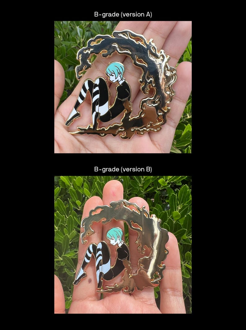 May include: Gold-colored metal pin featuring a seated anime-style figure with blue hair and black and white striped legs. The figure is surrounded by a stylized, flowing gold design. The pin is held in a hand.