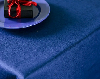 Puede incluir: Una pequeña caja de regalo negra con una cinta roja está sobre un plato azul. El plato está sobre un mantel azul.