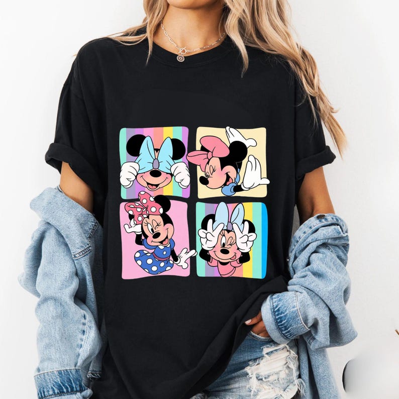 Może przedstawiać: Czarny t-shirt z kolorową grafiką Myszki Minnie w czterech r&oacute;żnych pozach. Każda poza znajduje się w kwadracie z tęczowym tłem. Myszka Minnie ma na sobie kokardy i stroje w r&oacute;żnych kolorach.