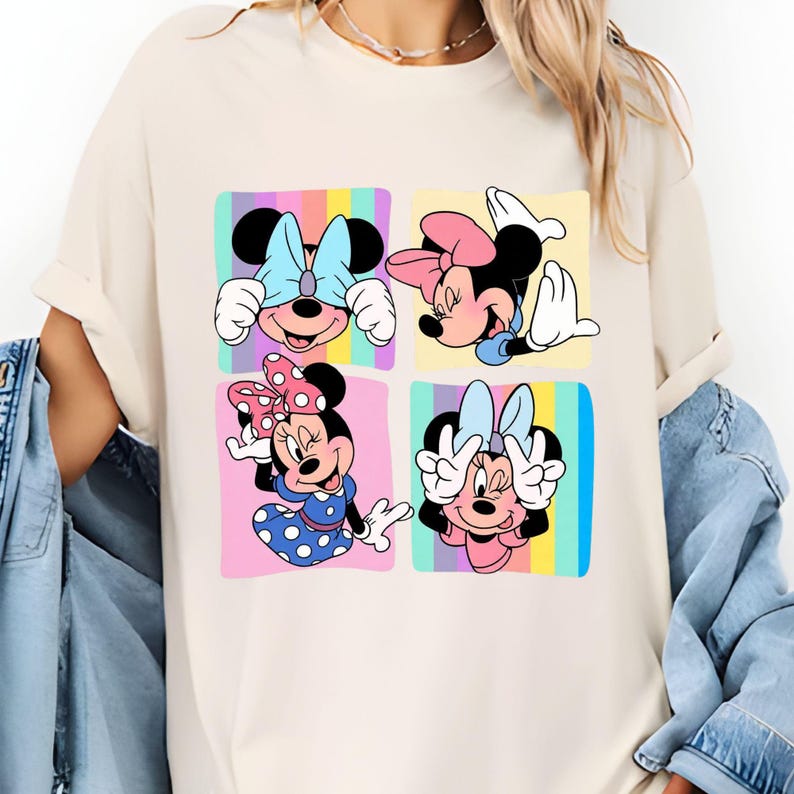 Może przedstawiać: Kremowy t-shirt z kolorową grafiką Myszki Minnie w czterech r&oacute;żnych pozach. Każda poza jest umieszczona na pastelowym, kwadratowym tle. Myszka Minnie ma na sobie kokardy i stroje w r&oacute;żnych kolorach.