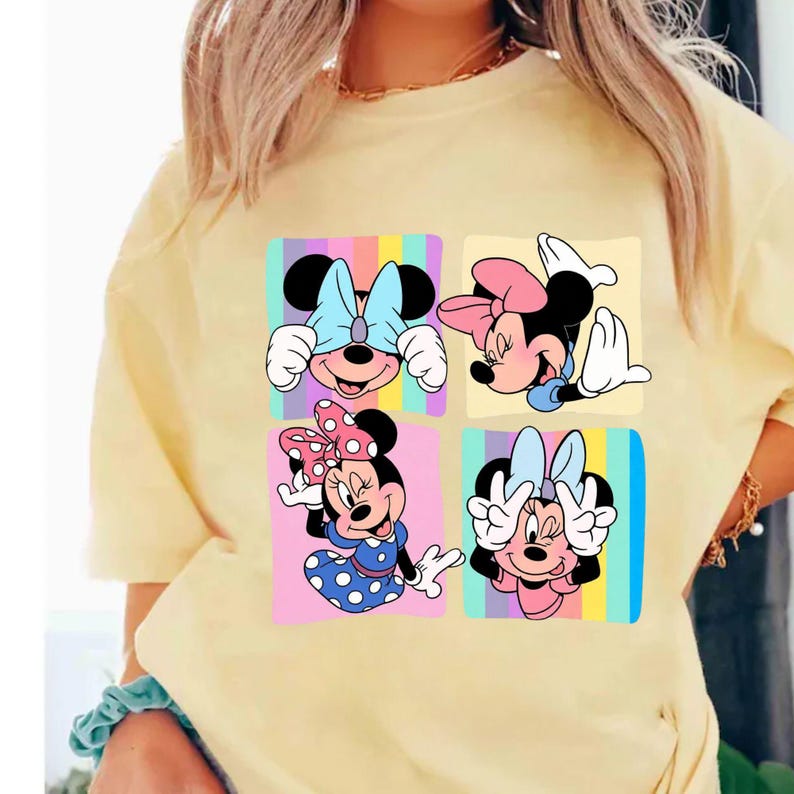 Może przedstawiać: Jasnoż&oacute;łta koszulka z kolorową grafiką Myszki Minnie w czterech r&oacute;żnych pozach. Każdy obraz Myszki Minnie jest umieszczony na pastelowym tle z tęczowymi paskami. Koszulka jest w stylu casual i wygodnym.