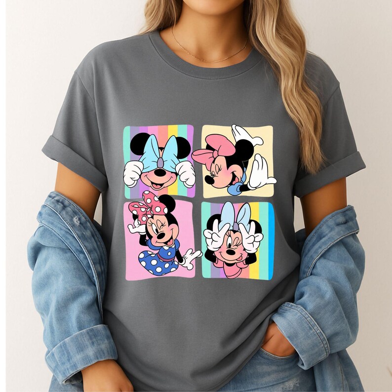Może przedstawiać: Szara koszulka z kolorową grafiką Myszki Minnie w czterech r&oacute;żnych pozach. Każdy kwadrat przedstawia Minnie z inną kokardą i wyrazem twarzy, na tle pastelowego tęczowego tła. Koszulka ma podwinięte rękawy.