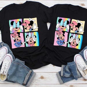 Może przedstawiać: Dwie czarne koszulki z kolorową grafiką Myszki Minnie. Każda koszulka ma cztery kwadraty z r&oacute;żnymi pozami Myszki Minnie na tęczowym tle. Koszulki są połączone z niebieskimi dżinsami i białymi trampkami.