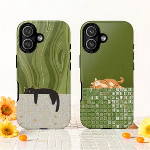Puede incluir: Dos fundas para teléfono con diseños de gatos. Una funda presenta un gato negro descansando sobre un patrón de mosaico, sobre un fondo verde veteado. La otra funda tiene un gato atigrado naranja descansando sobre un patrón de azulejos verdes, con un fondo verde liso.