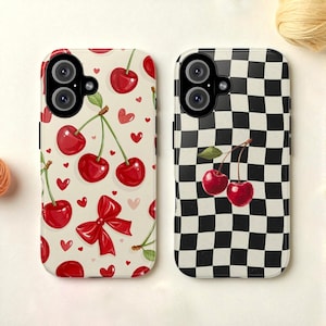 Op de afbeelding: Twee telefoonhoesjes met kersendesigns. Eén hoesje heeft een crèmekleurige achtergrond met rode kersen, hartjes en een strik. De andere hoes heeft een zwart-wit geblokt patroon met kersen. Beide hoesjes hebben een camera-uitsparing.