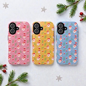 Könnte beinhalten: Drei Handyhüllen mit Weihnachtsmotiven. Die Hüllen sind rosa, gelb und blau und zeigen jeweils ein sich wiederholendes Muster aus Weihnachtsmann-Gesichtern, Zuckerstangen und Geschenken. Jede Hülle hat einen Kameraausschnitt und Seitentasten.