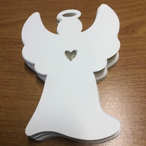 May include: A stack of white paper angel ornaments with a heart cut out in the center. The angels have a halo and wings.