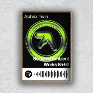Puede incluir: Póster enmarcado con el logo de Aphex Twin en verde neón sobre fondo negro. El texto blanco dice "Aphex Twin" y "Selected Ambient Works 85-92". Un código de barras de Spotify está en la parte inferior.
