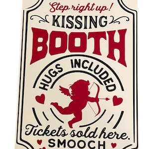Puede incluir: Un letrero de metal blanco con letras negras y rojas que dice "Step right up! Kissing Booth Hugs Included Tickets sold here. Smooch 25¢ Each". Un cupido rojo con alas y una flecha está en el centro del letrero.
