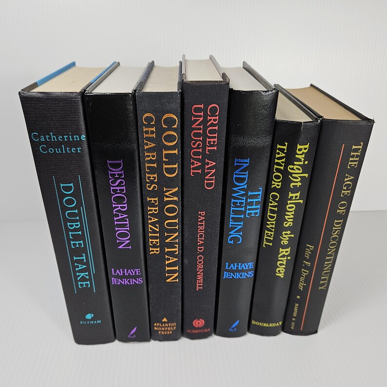 May include: A collection of seven hardcover books with black covers. Titles include "Double Take," "Desecration," "Cold Mountain," "Cruel and Unusual," "The Indwelling," "Bright Flows the River," and "The Age of Discontinuity."