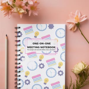 Colorful One-on-One Meeting Notebook spiral planner on pink desktop with flowers and office accessories