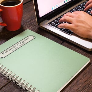 Medical Care Organizer notebook beside a laptop during everyday planning and organization.