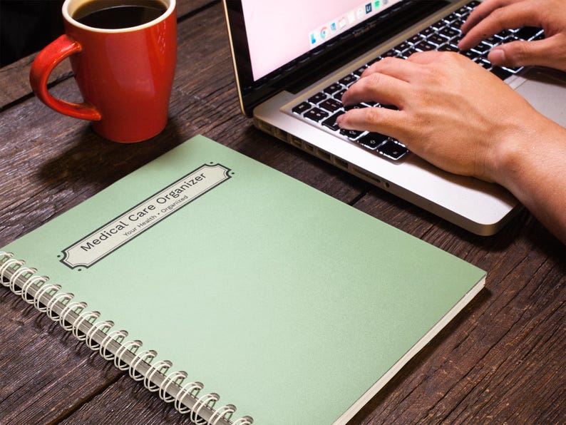 Medical Care Organizer notebook beside a laptop during everyday planning and organization.
