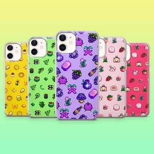 May include: Five phone cases with pixelated food and drink designs. The cases are yellow, green, purple, pink, and red. The designs include sushi, grapes, strawberries, and bottles. The cases have a clear border.
