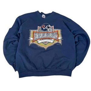 Könnte beinhalten: Marineblaues Sweatshirt mit einem Vintage-Grafik eines Football-Helms und dem Wort "BEARS". Die Grafik enthält auch den Text "Football Tradition". Das Sweatshirt hat einen Rundhalsausschnitt.