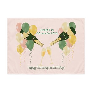 May include: A light pink rectangular decorative cloth with a champagne theme. The design includes champagne bottles, glasses, balloons, and the text "EMILY is 25 on the 25th" and "Happy Champagne Birthday!"