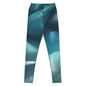 Puede incluir: Leggings de talle alto con un patrón abstracto y fluido en tonos azul verdoso profundo, azul marino y azul claro suave. El diseño consiste en formas curvas suaves y superpuestas que crean un efecto de degradado en toda la superficie.
