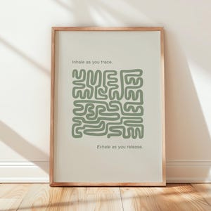 Peut inclure: Une affiche encadrée avec un fond beige clair et un motif abstrait vert sauge. Le texte "Inhale as you trace" et "Exhale as you release" est imprimé au-dessus et en dessous du motif. Le cadre est de couleur marron clair.