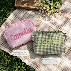 Puede incluir: Dos estuches rectangulares con cremallera, bordes con volantes y estampado de cuadros vichy. Uno es de color rosa claro con el texto bordado en rosa oscuro Camelia, y el otro es verde con el texto bordado en verde aguacate Sophie.