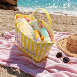 May include: A yellow and white striped tote bag with two handles, containing a book with the word Italy visible on the cover, a yellow bottle, and a light blue bottle. The bag features purple embroidered script text on the exterior side.