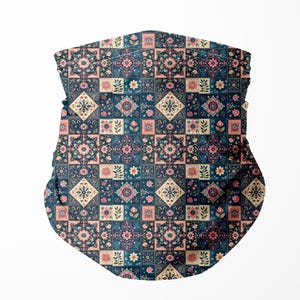 Könnte beinhalten: Ein gemusterter Mund-Nasen-Schutz mit dunkelblauem Hintergrund und einem sich wiederholenden Blumendesign in Rosa, Creme und Türkis. Das Muster besteht aus Quadraten und Rauten. Der Mund-Nasen-Schutz ist ein Halstuch.