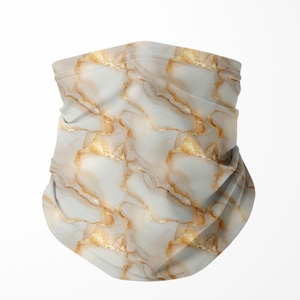 May include: A neck gaiter with a white and gold marble pattern. The fabric is folded and draped, creating a textured appearance. The design features gold veining against a white background, resembling natural stone.