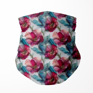May include: A neck gaiter with a repeating floral pattern. The design features watercolor-style red and pink flowers with teal leaves on a white background. The fabric is folded at the top.