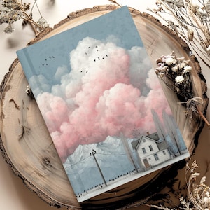 May include: A hardback journal featuring a printed illustration of a white house nestled beneath towering, voluminous pink and blue clouds. A utility pole stands near the house, and a flock of small black birds flies across the sky.