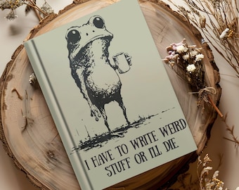 May include: A notebook with a frog illustration holding a mug. The frog is black and white, with large eyes. The notebook has the text "I HAVE TO WRITE WEIRD STUFF OR I'LL DIE" in black.