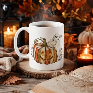 May include: A white ceramic mug featuring a colorful illustration of a carved pumpkin shaped like a stack of books with a small ghost draped over the top. The pumpkin has a carved jack-o'-lantern face and intricate patterns on its book-like sections.