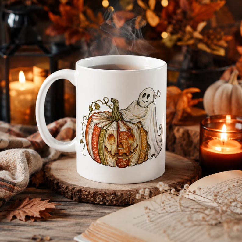 May include: A white ceramic mug featuring a colorful illustration of a carved pumpkin shaped like a stack of books with a small ghost draped over the top. The pumpkin has a carved jack-o'-lantern face and intricate patterns on its book-like sections.