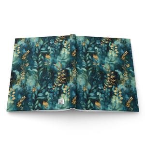 May include: A hardcover book laid open to show the front and back covers. The cover features a dark teal and blue watercolor background with a repeating pattern of golden botanical illustrations, including leaves, ferns, and small flowers.