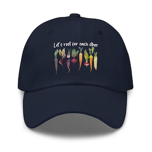 Könnte beinhalten: Marineblaue Baseballkappe mit einer Aquarellillustration verschiedener Wurzelgemüse. Auf der Kappe steht in weißer Schrift der Text "Let's root for each other". Ein stilvolles und bequemes Accessoire.