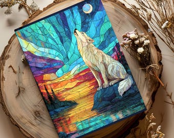 May include: A rectangular notebook featuring a stained glass style illustration of a wolf howling at a crescent moon. The artwork displays vibrant blue, teal, purple, and orange hues depicting a landscape with water and trees.