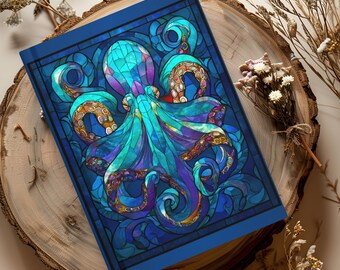 May include: A blue notebook with a stained-glass design featuring a colorful octopus. The octopus is depicted in shades of blue, teal, purple, and orange. The notebook has a dark blue border and is resting on a wooden surface.