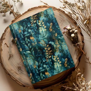 May include: A rectangular notebook featuring a dark teal and blue watercolor background with a pattern of gold-colored botanical leaves and stems. The cover has a smooth finish and displays a dense arrangement of foliage across the entire surface.